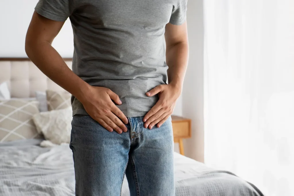 Man holding lower abdomen and groin area indicating genital health concern