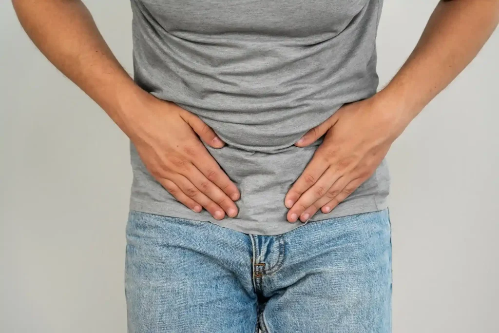 Man holding lower abdomen experiencing pelvic or groin pain